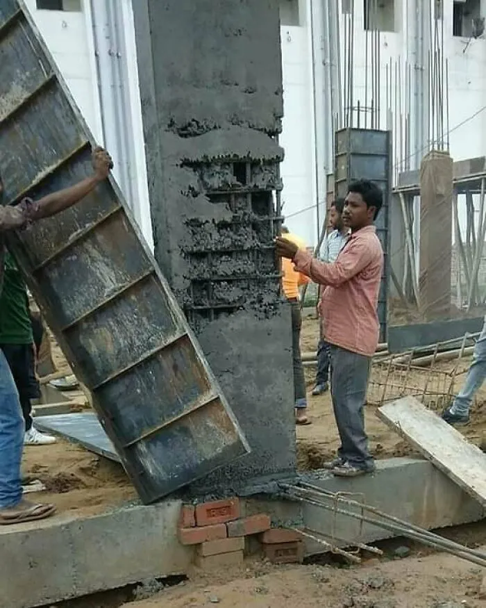 Trabajadores en una obra, retirando encofrado de hormigón, ilustran fallos de arquitectura.
