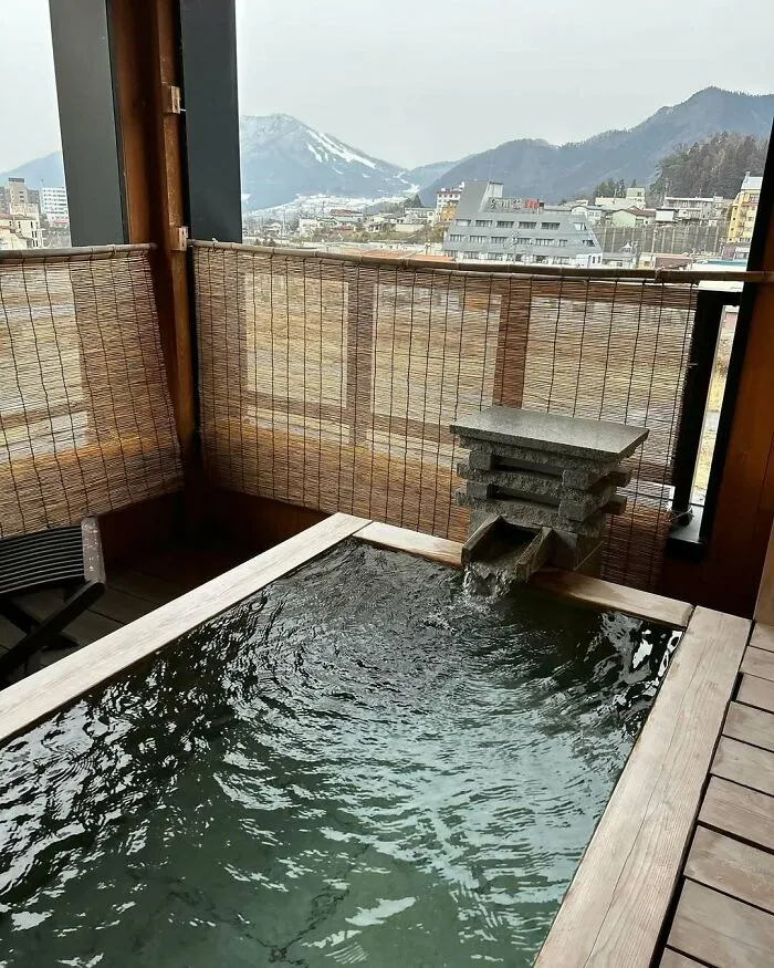 Outdoor hot spring bath with mountain view in Japan, showcasing serene scenery and traditional design elements.