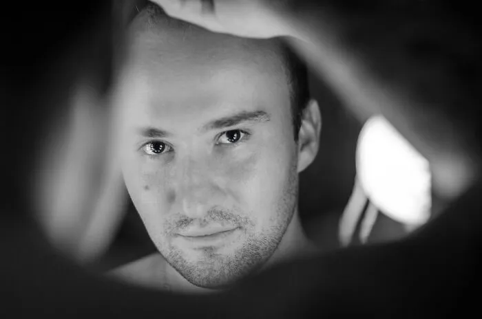 A person staring into a mirror, capturing reflections in a dimly lit room, relating to common superstitions.