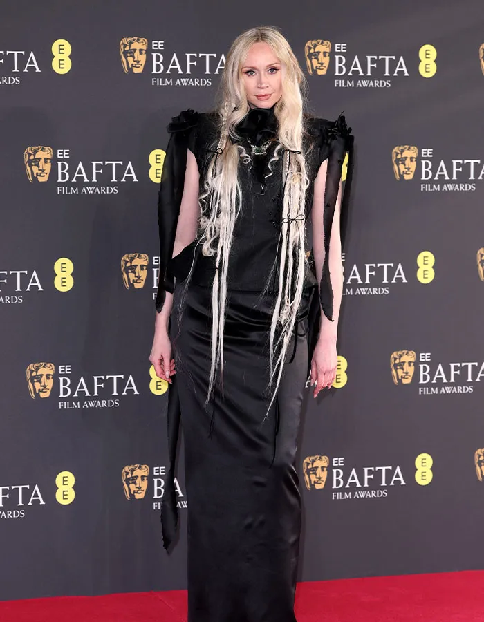 Person in striking black dress at BAFTA red carpet, showcasing daring outfits and head-turning style.