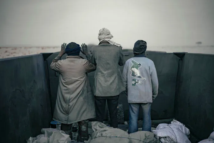 Men Pray At Dusk, Facing Towards Mecca As The Iron Ore Train Rides Through The Desert