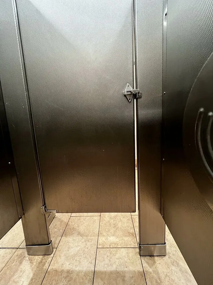 Public restroom stall with metallic door slightly ajar, showing typical USA architecture that confuses some foreigners.