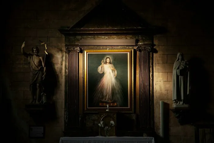 Religious painting in a dimly lit church, surrounded by statues and dramatic lighting, conveying a potentially creepy aura.