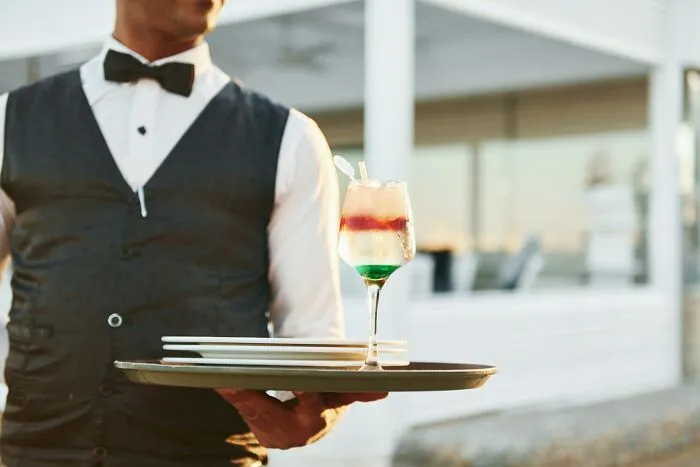 Waiter in formal attire serving drinks at a wedding, addressing common guest dislikes at events.
