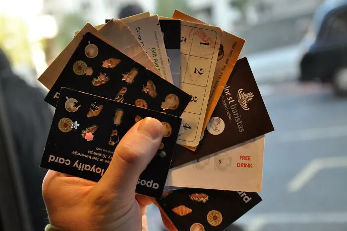 Hand holding various loyalty and gift cards, symbolizing sentimental items people carry despite being rather useless.