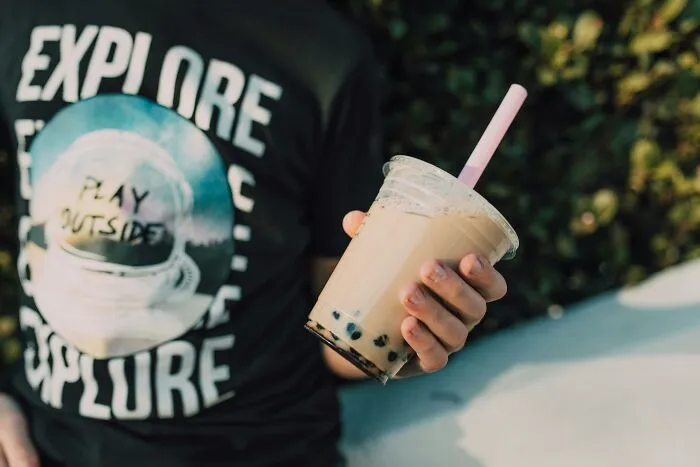 Person in a graphic T-shirt holding bubble tea, a sentimental yet rather useless item.