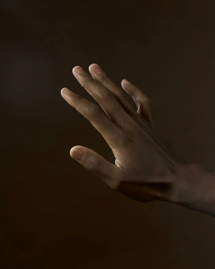 Hand raised against a dark background related to superstitions and itchy hands belief.