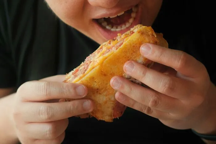 Person eating sloppy food with hands, ignoring common social rules for dining etiquette.