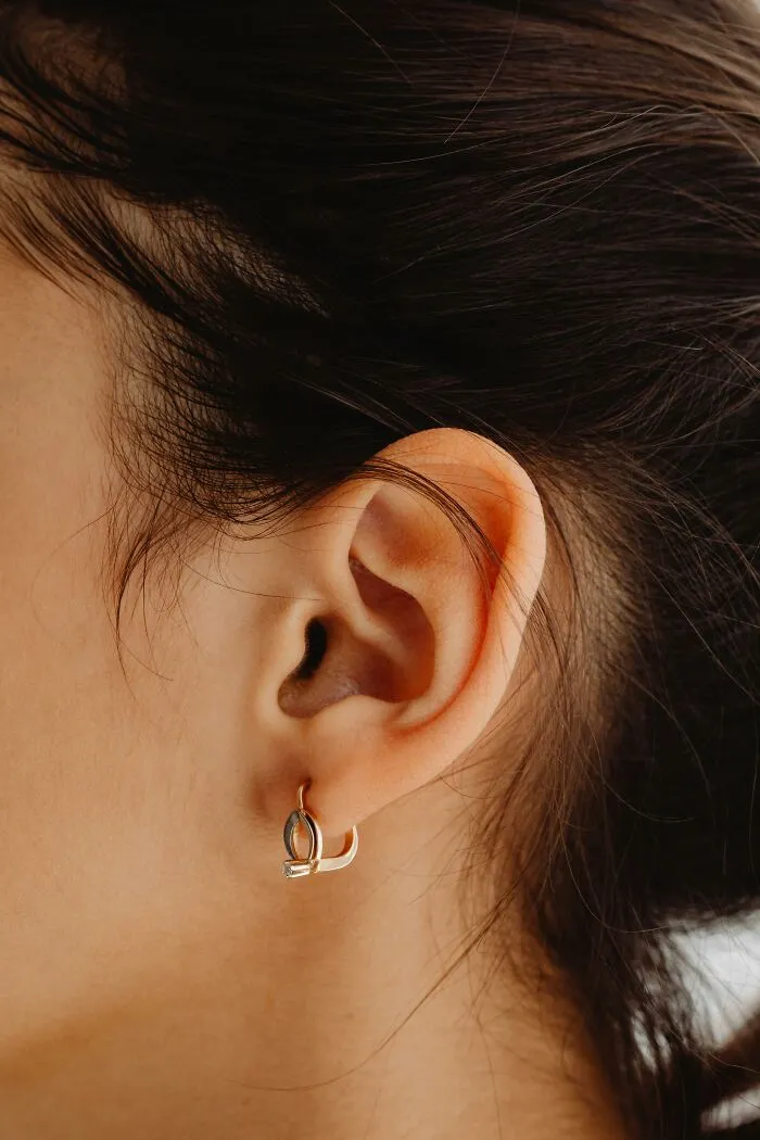 Close-up of an ear with hoop earring, discussing superstitions related to hot red ears.