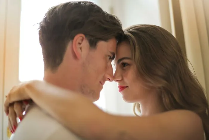 Two people face each other closely, showcasing affection and intimacy, possibly ignoring social rules.
