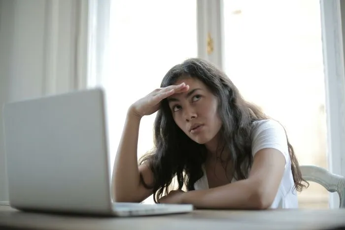 Person pondering over laptop, potentially contemplating social rules people ignore.