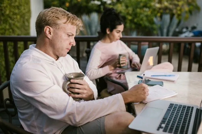 A couple enjoying coffee together, working on laptops, demonstrating love and care.