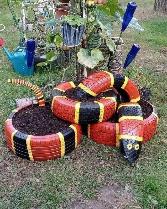 Painted tires arranged as a snake garden decoration, inspiring recycling in a backyard setting.