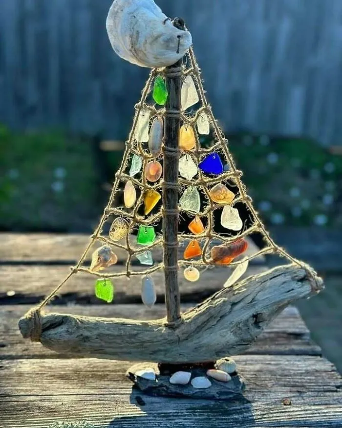 Decorative sailboat made from recycled driftwood and colorful glass, showcasing creative recycling.