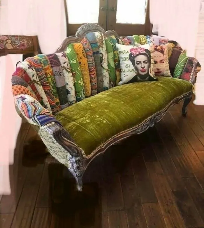 Recycled patchwork couch with colorful cushions and green velvet seat on a wooden floor.