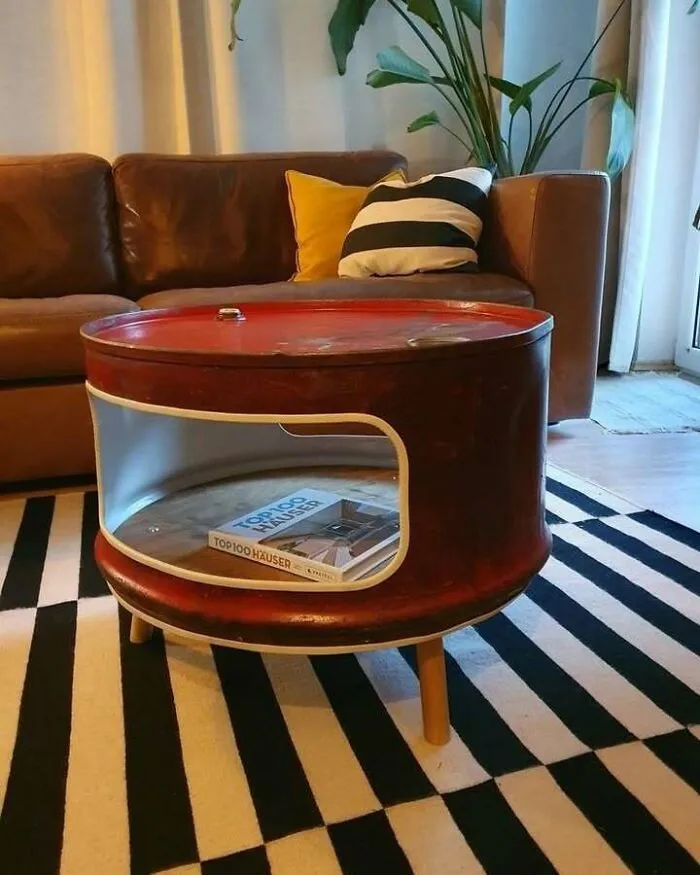 Recycled barrel coffee table in a cozy living room, showcasing stylish upcycling with plants and cushions.