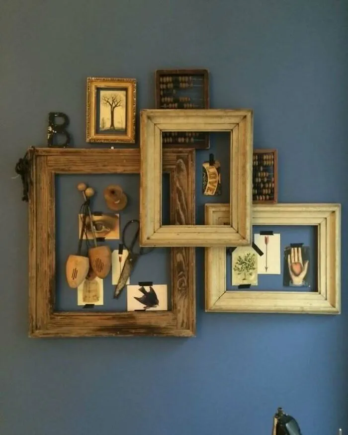 Recycled art piece with wooden frames and vintage elements on a blue wall.