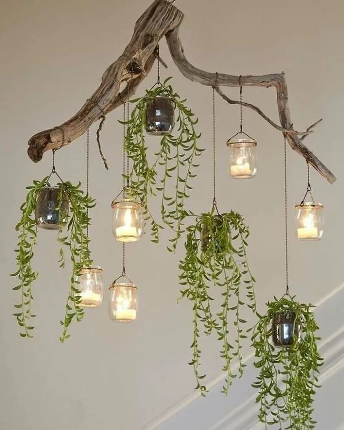 Hanging branch with recycled jar candles and greenery creating a decorative, eco-friendly light fixture.
