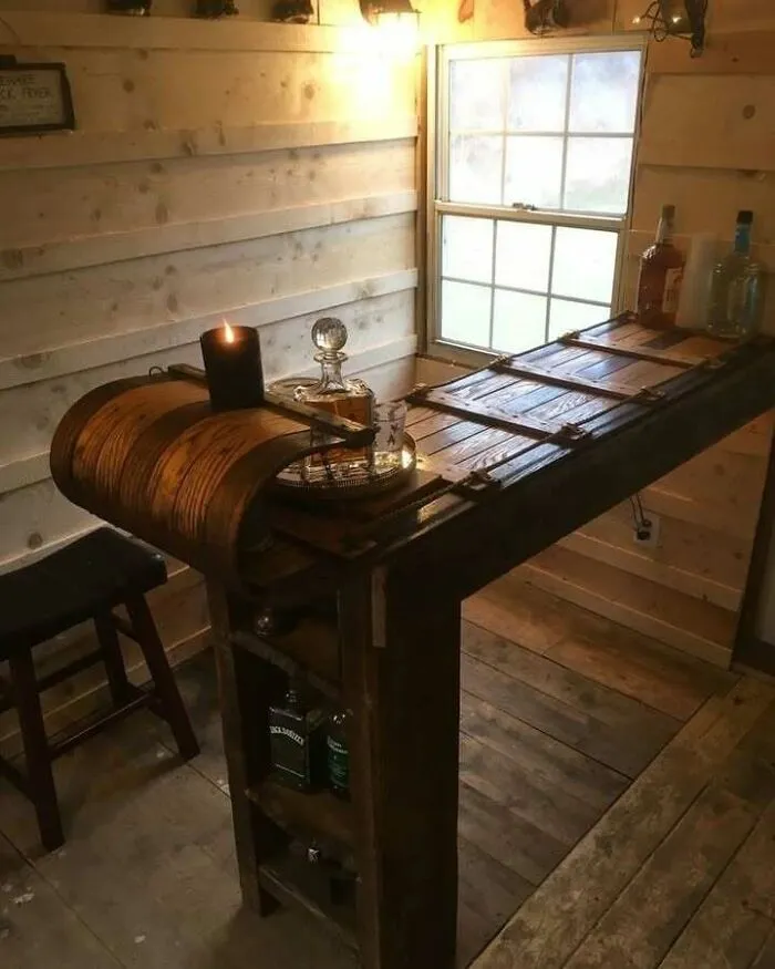 Recycled materials create a unique home bar with wooden barrel accents and bottles.