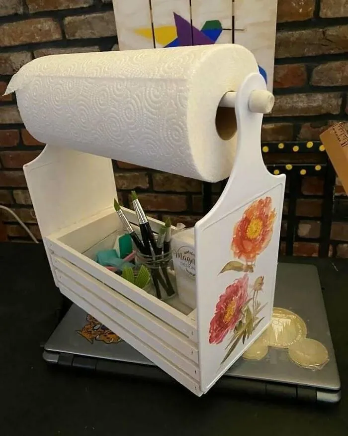 Handcrafted paper towel holder with floral design repurposes wood for creative recycling inspiration.