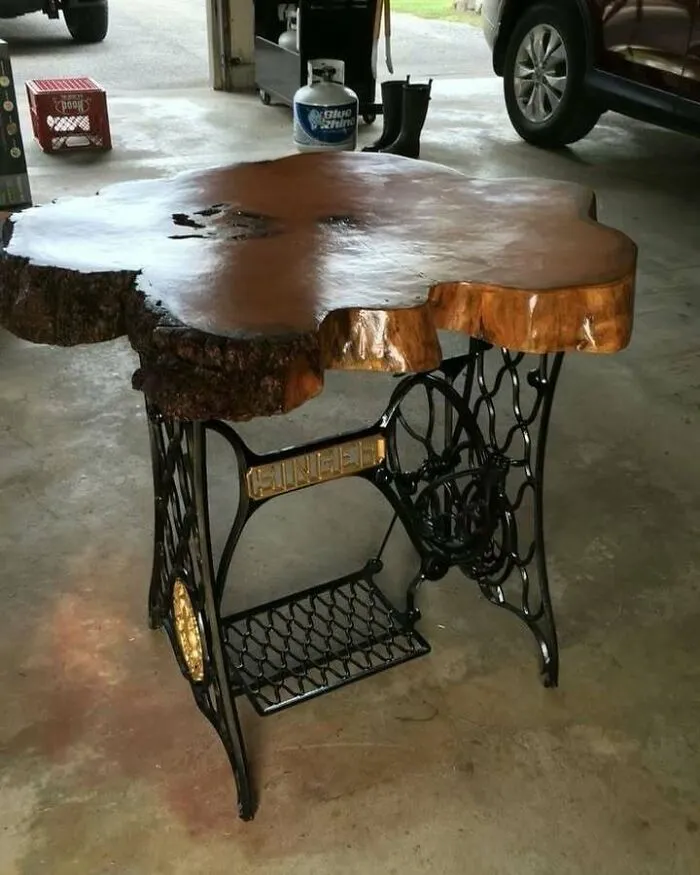 Recycled vintage sewing machine base with a wooden slab tabletop in a garage setting.