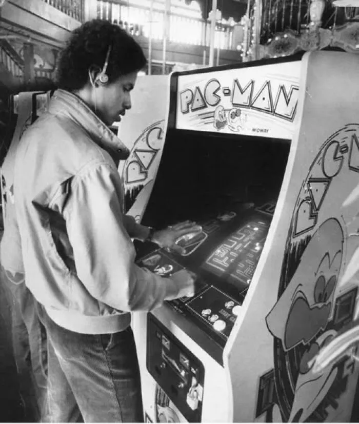 Hombre escuchando su walkman mientras juega al Pacman, la experiencia ochentera resumida en una foto