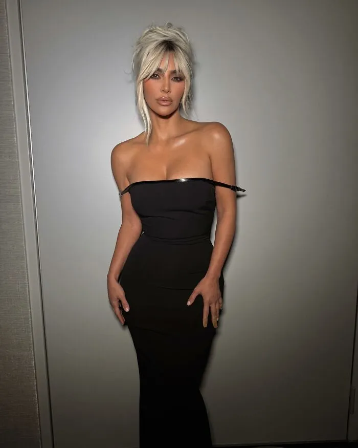 Person in a black dress, posing confidently against a plain background, exemplifying a not-self-made-celeb.