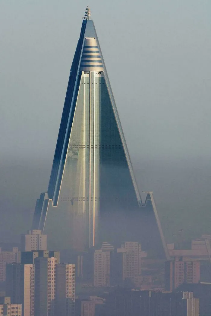 Massive pyramid-shaped skyscraper towering over smaller buildings, illustrating a scarily big structure for megalophobia.