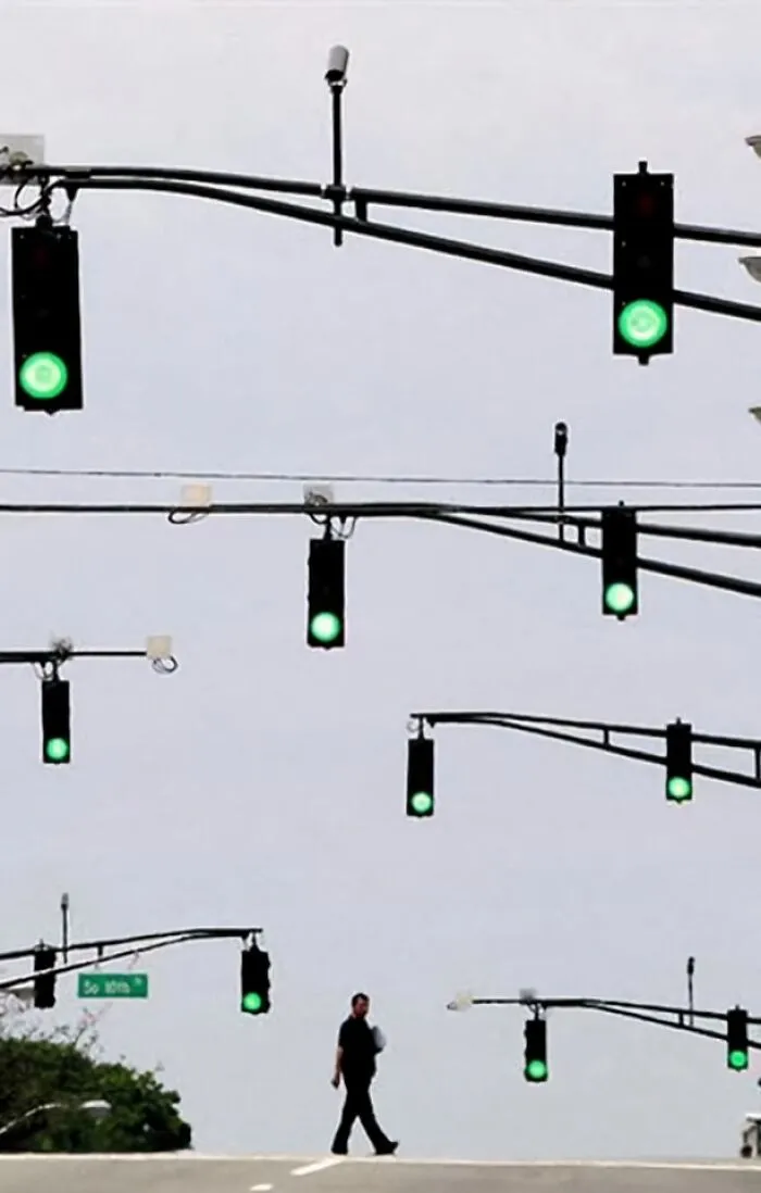 Semáforos en verde, múltiples niveles, persona cruzando; imagen aleatoria y absurda.