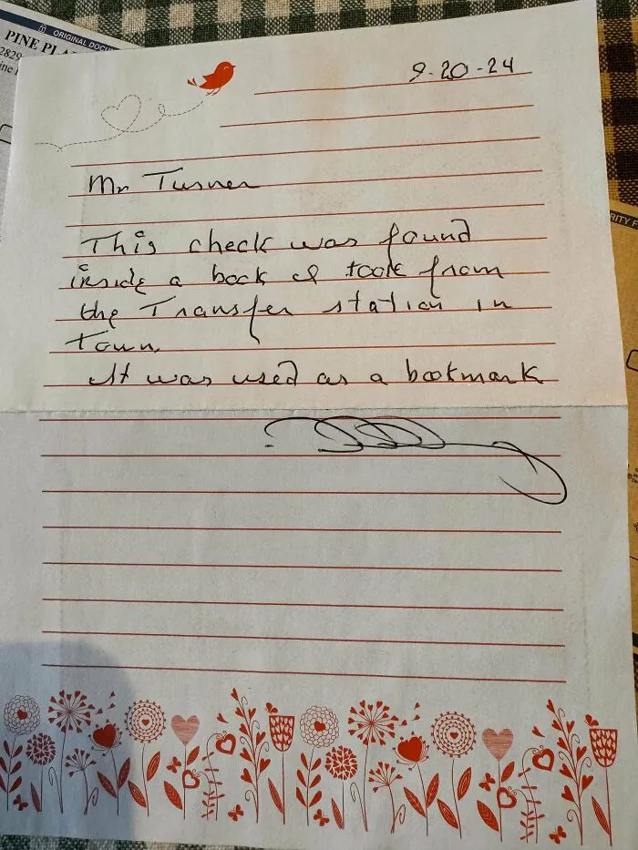 Handwritten note on floral paper about a check used as a bookmark by book lovers.