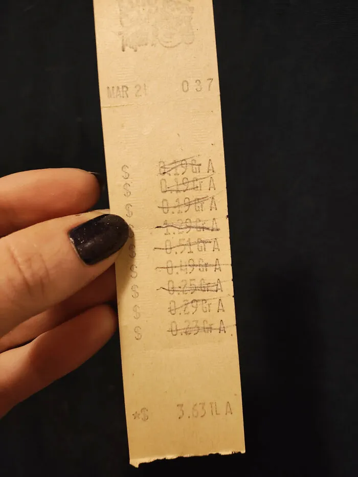 Old receipt used as a bookmark, held by a person with dark nail polish.
