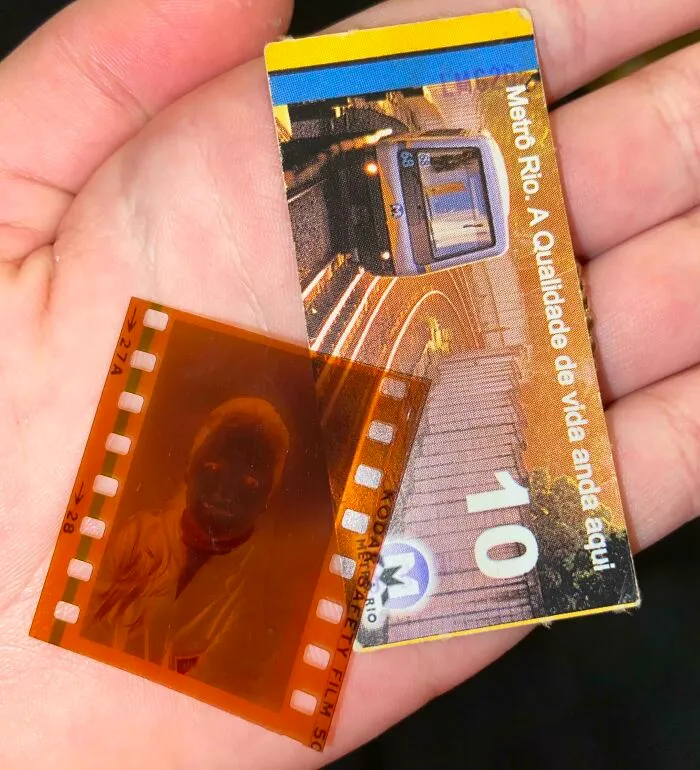 Hand holding unique bookmarks: a Metro Rio ticket and a film negative.