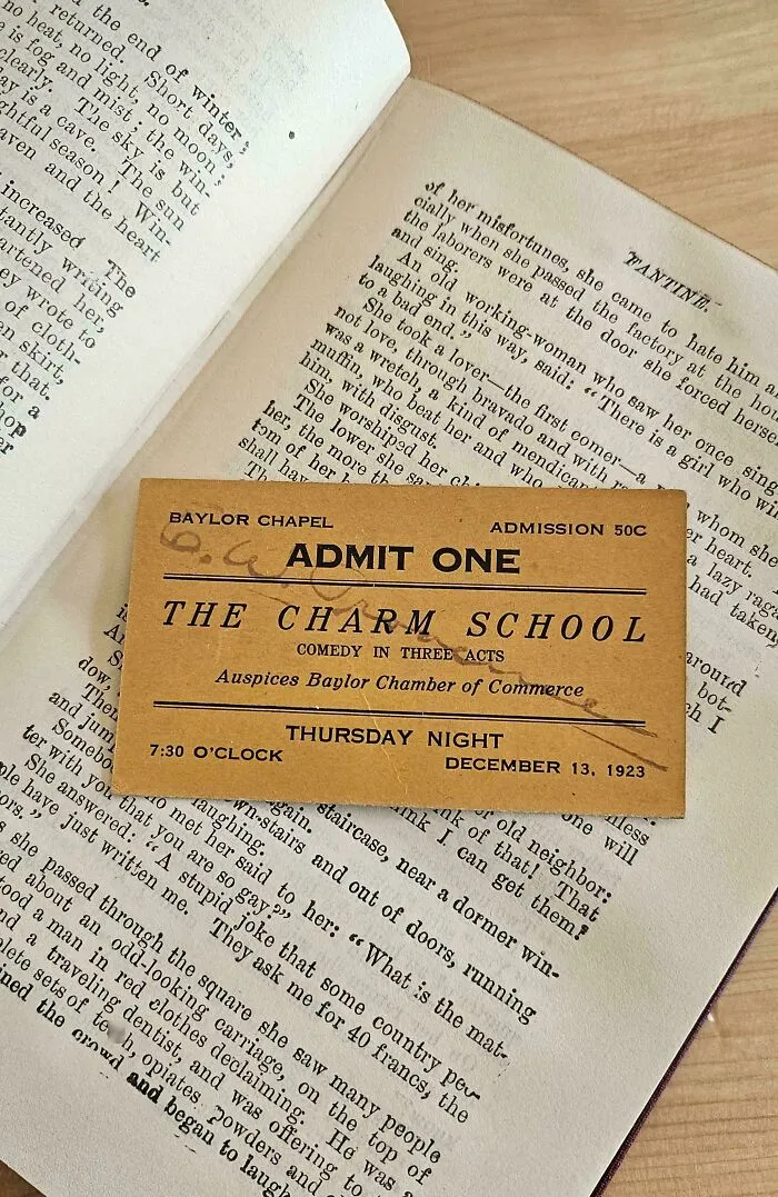 Vintage theater ticket used as a bookmark in an open book.
