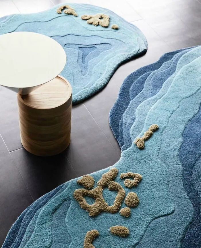 Alfombra azul con diseño de geografía, junto a mesa redonda blanca, ejemplifica diseños poco prácticos en la realidad.
