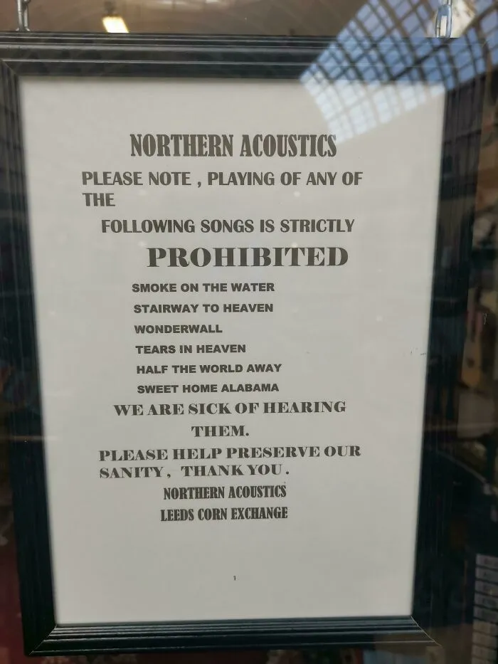 Sign listing prohibited songs in a humorous passive-aggressive tone at Northern Acoustics, Leeds Corn Exchange.