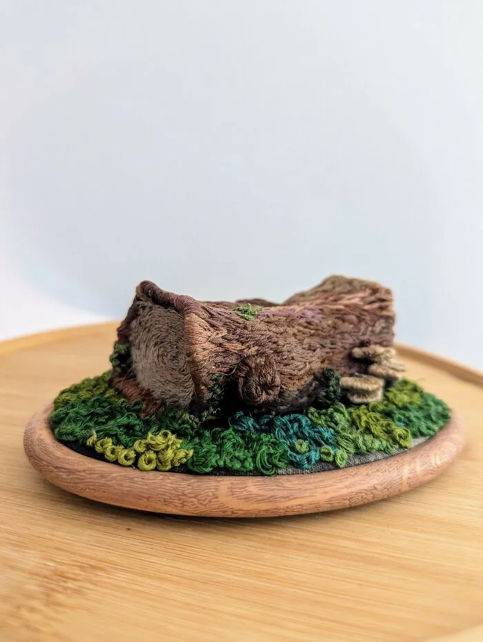 3D embroidered tree stump and grass on a wooden base showcasing incredible and beautiful embroidery skills.