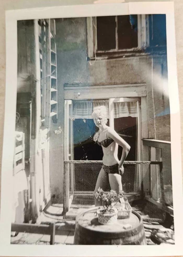 Vintage candid glimpse of a woman in a swimsuit on a balcony, capturing an intimate moment from the past not found in history books.