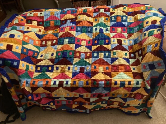 Colorful crochet blanket featuring a detailed pattern of houses, showcasing incredible creativity by crochet enthusiasts.
