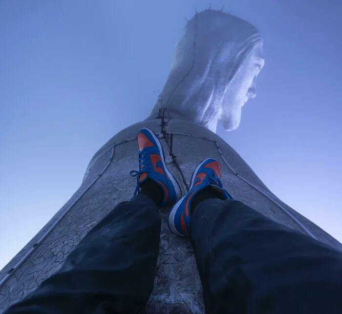 Persona apoyada en la base del Cristo Redentor, con vista hacia la estatua, ofreciendo una perspectiva distinta.