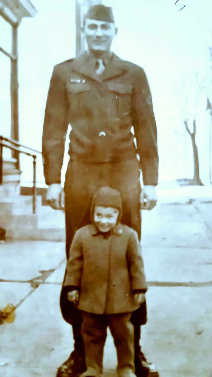 Vintage photo of a soldier standing behind a smiling child, one of the candid glimpses into the past moments