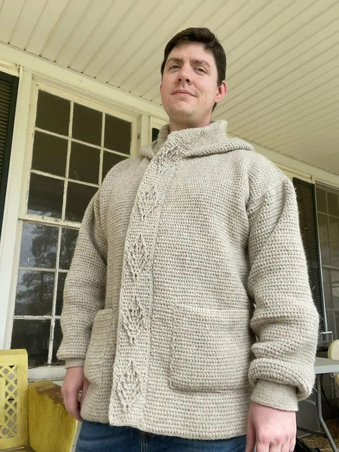 Man wearing a handmade crochet sweater with textured patterns and pockets, showcasing crochet craftsmanship and style.