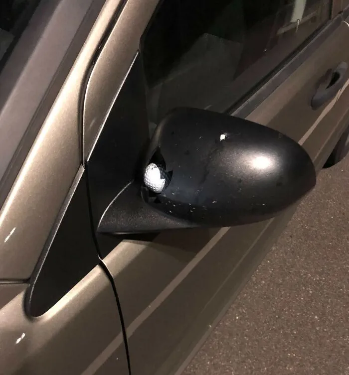 Espejo lateral de auto con pelota incrustada, ejemplo de accidente caro.
