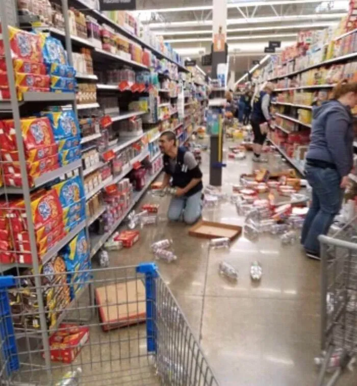 Empleado recogiendo productos en pasillo desordenado en supermercado, relacionado con clientes ignorantes y frustrantes.