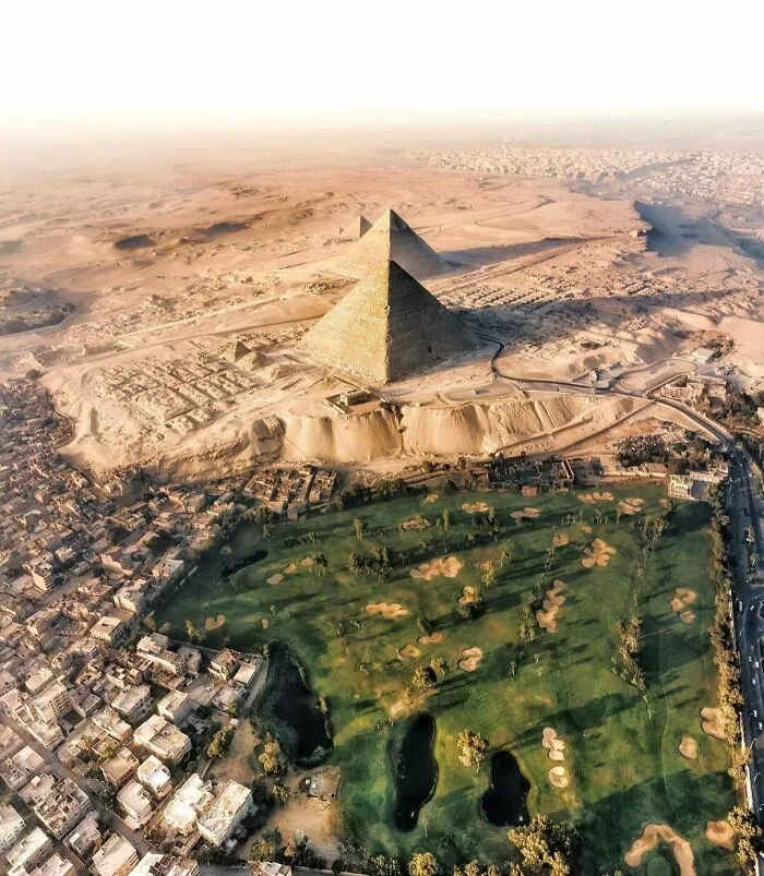 Vista aérea de las Pirámides de Egipto junto a un campo de golf, mostrando una perspectiva distinta.