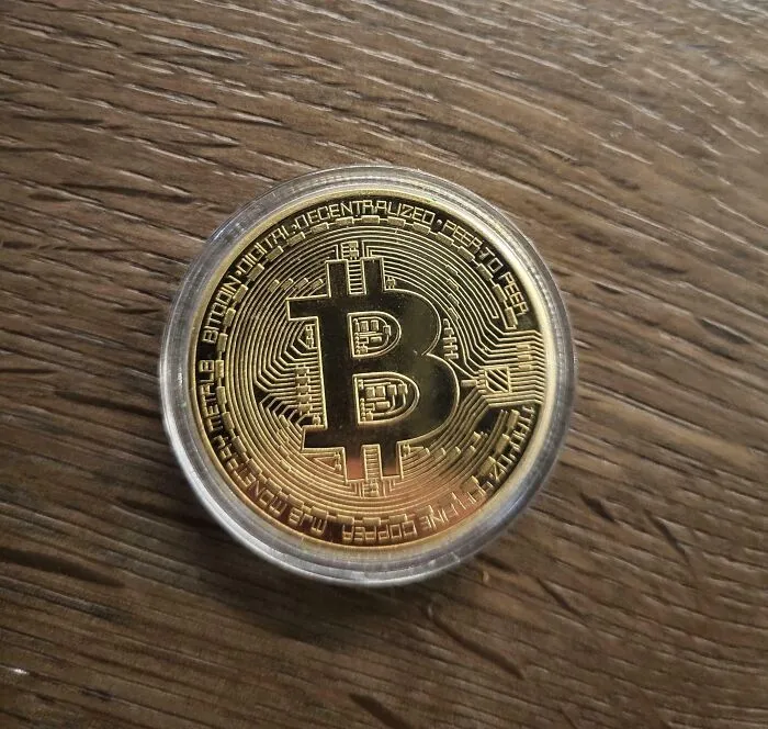 Moneda de bitcoin sobre una mesa de madera.