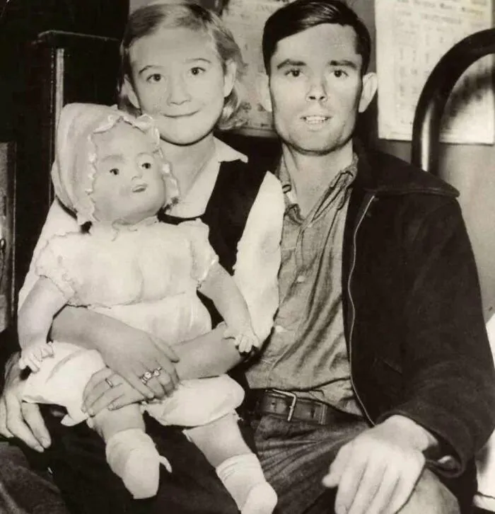 Pareja vintage con muñeca en un entorno inquietante del pasado.