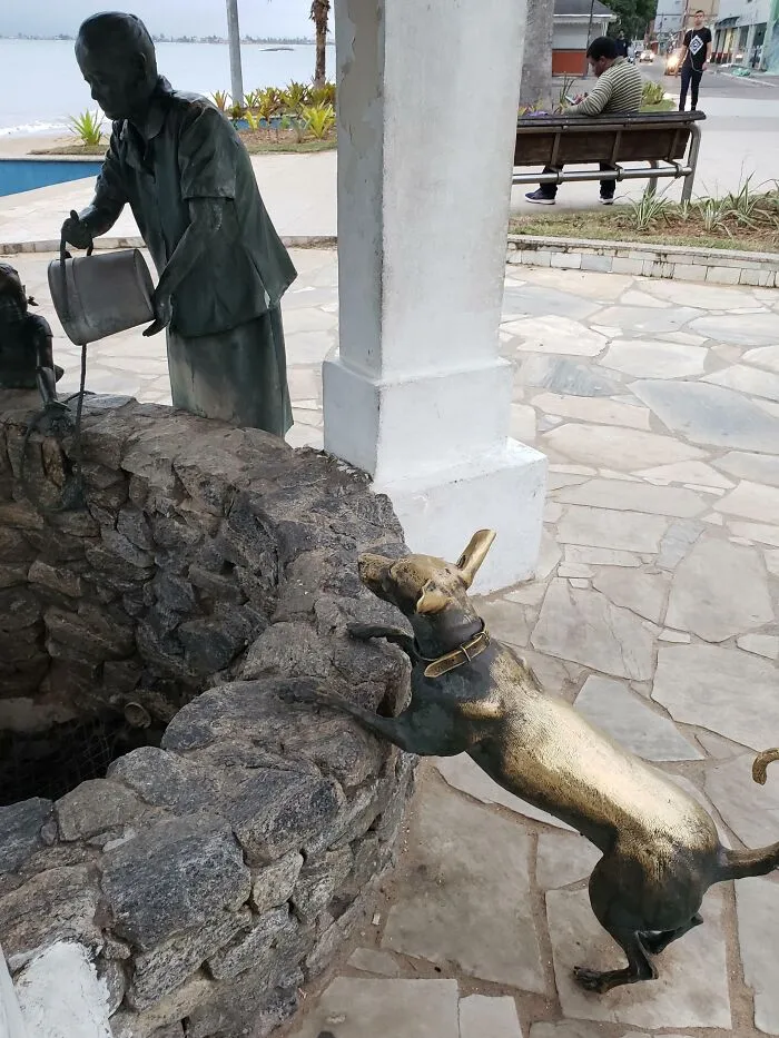 Estatua de un perro desgastada donde la gente la acaricia