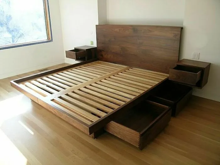 Wooden bed frame with drawers in a minimalist bedroom, illustrating poorly-aging interior design trends.