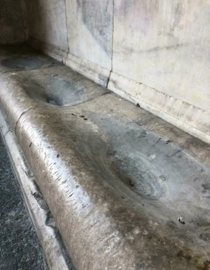 Stone surface worn down by time and use, showcasing a smooth indentation.