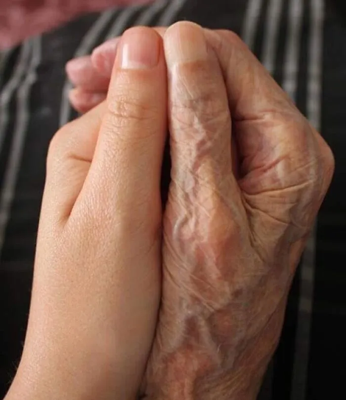 A youthful hand holds a weathered hand, illustrating transformation by time and use.